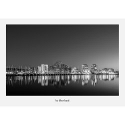 Sort-hvid bylandskab af Vejle med spejlinger i vandet og byens skyline fanget i roligt aftenlys.