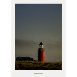 R�dt fyrt�rn st�ende i klitterne under himmel i den bl� time, med lys i lanternen og d�mpet aftensstemning.