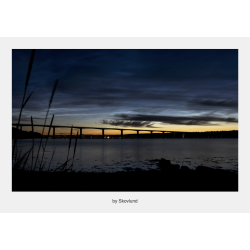 Lysende natskyer over Vejle Fjord med d�mpet bl�t lys, vandflade og stille stemning efter solnedgang.