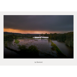 Haraldsk�r beliggende i en oversv�mmet eng under en br�ndende himmel med regntunge skyer, hvor vand, lys og landskab smelter sammen i et dramatisk, nordisk udtryk.